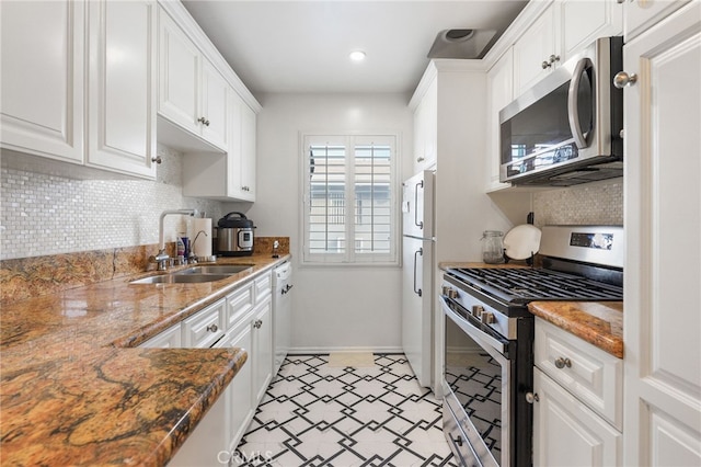 kitchen with sink, backsplash, stainless steel appliances, white cabinets, and stone countertops