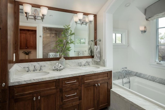 bathroom featuring vanity, a healthy amount of sunlight, a relaxing tiled tub, and a chandelier