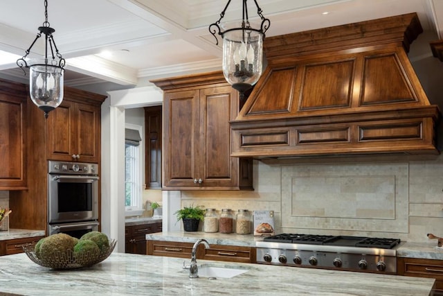 kitchen featuring appliances with stainless steel finishes, sink, pendant lighting, and an inviting chandelier