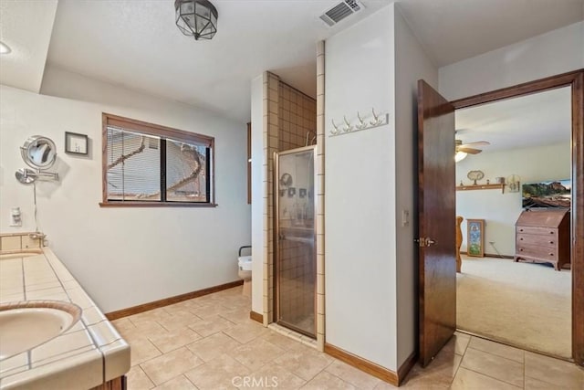 bathroom with ceiling fan, vanity, a shower with shower door, and tile patterned flooring