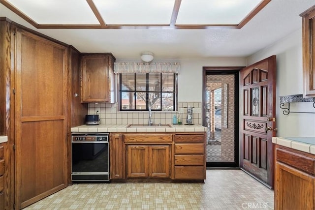 kitchen featuring sink, backsplash, tile counters, and dishwasher