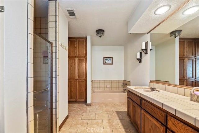 bathroom featuring vanity, tile patterned flooring, independent shower and bath, and a textured ceiling