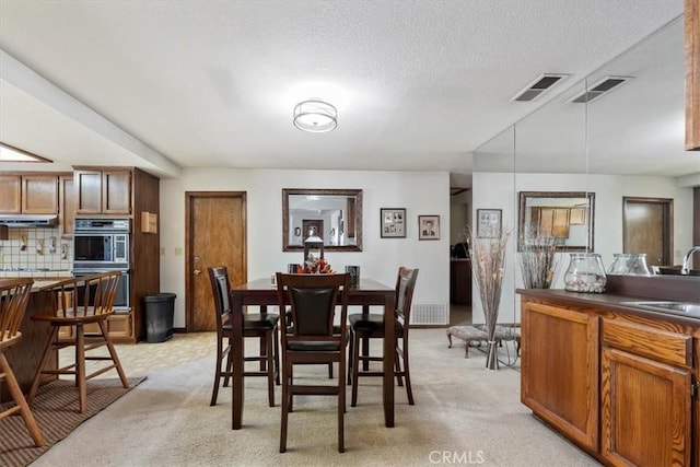 carpeted dining room featuring sink and a textured ceiling