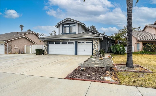 view of front of house with stone siding, fence, concrete driveway, a front yard, and an attached garage