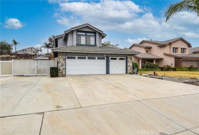 view of front of home with a gate, fence, driveway, a garage, and stone siding