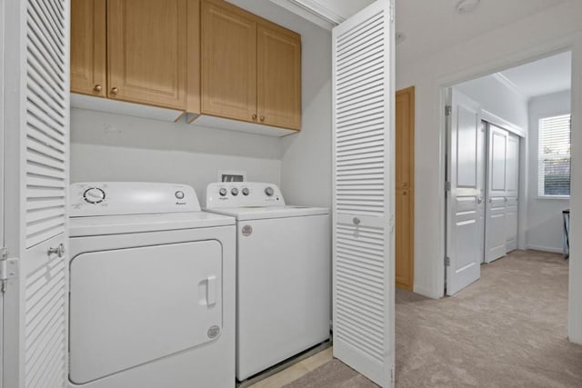 clothes washing area with cabinets, crown molding, light carpet, and washer and clothes dryer