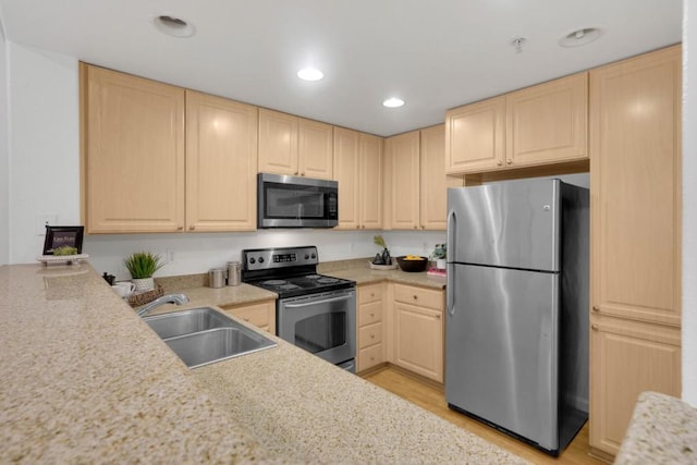 kitchen featuring light stone counters, sink, light hardwood / wood-style flooring, and appliances with stainless steel finishes