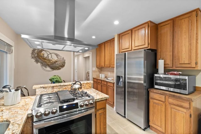 kitchen with light stone counters, appliances with stainless steel finishes, island range hood, and backsplash