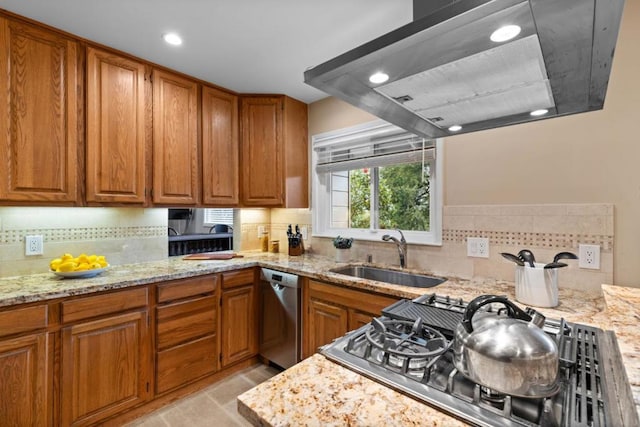 kitchen with light stone counters, dishwasher, sink, and wall chimney range hood