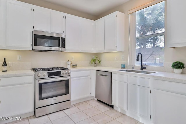 kitchen with sink, light tile patterned floors, stainless steel appliances, and white cabinets