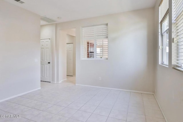 spare room featuring a wealth of natural light and light tile patterned floors