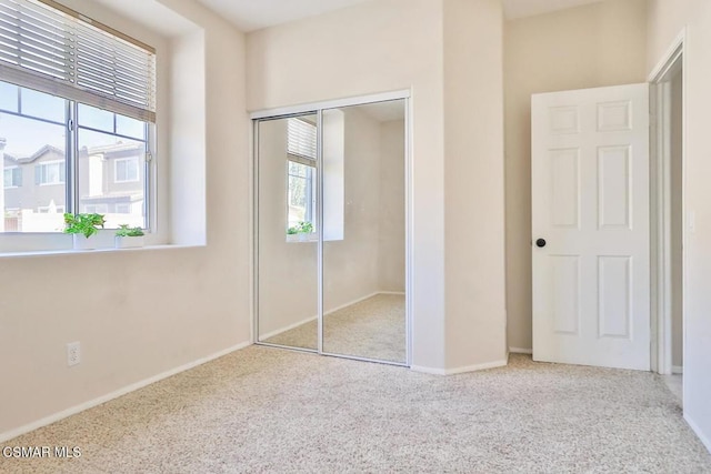 unfurnished bedroom featuring multiple windows, light colored carpet, and a closet