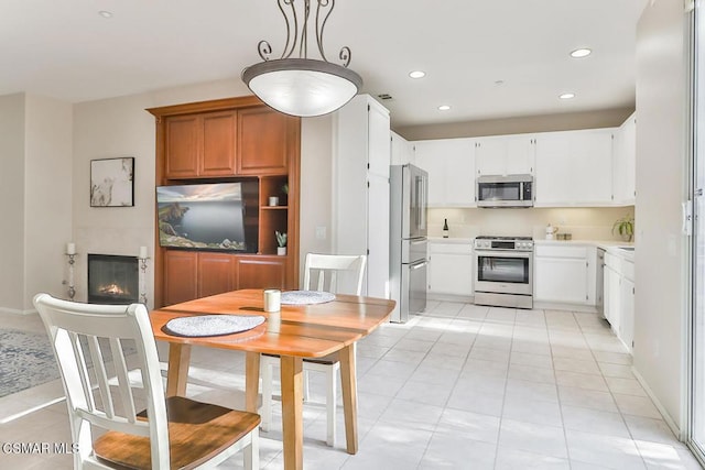 kitchen featuring pendant lighting, white cabinetry, stainless steel appliances, and light tile patterned flooring