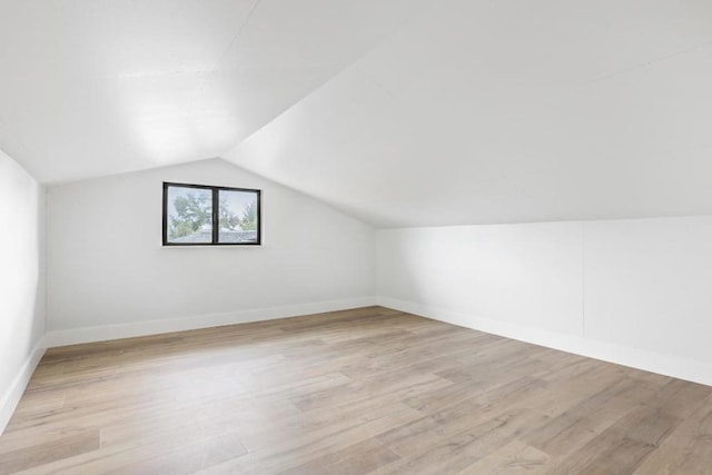 additional living space with vaulted ceiling and light wood-type flooring