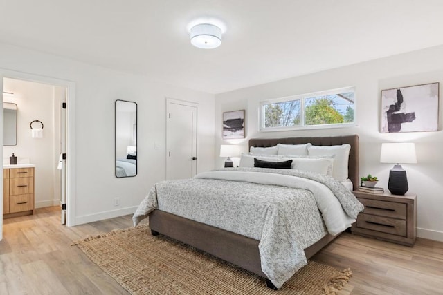 bedroom featuring connected bathroom and light hardwood / wood-style floors