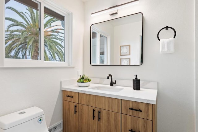 bathroom with plenty of natural light, toilet, and vanity