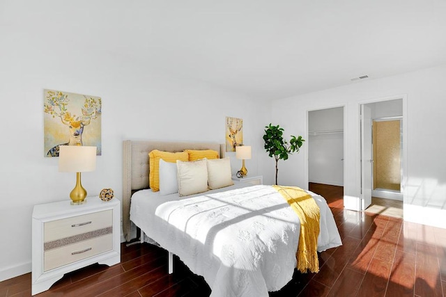 bedroom featuring a walk in closet, dark hardwood / wood-style flooring, and a closet