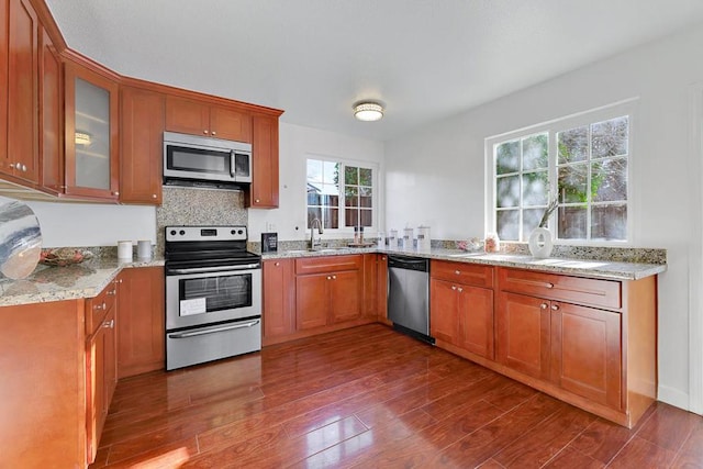 kitchen featuring light stone counters, appliances with stainless steel finishes, sink, and hardwood / wood-style floors