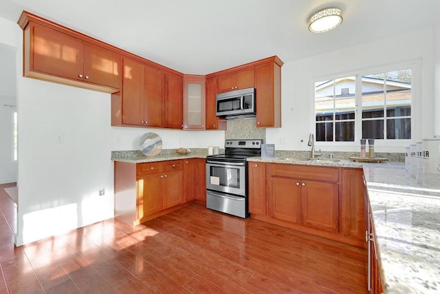 kitchen with light stone counters, sink, stainless steel appliances, and light wood-type flooring