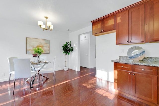 kitchen with light stone countertops, a chandelier, dark hardwood / wood-style flooring, and decorative light fixtures