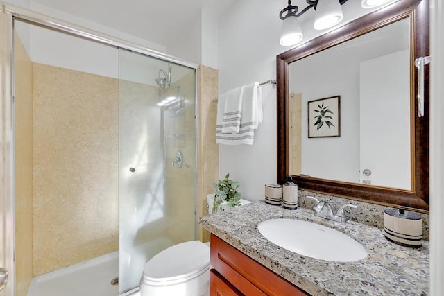 bathroom featuring vanity, a shower with shower door, and toilet