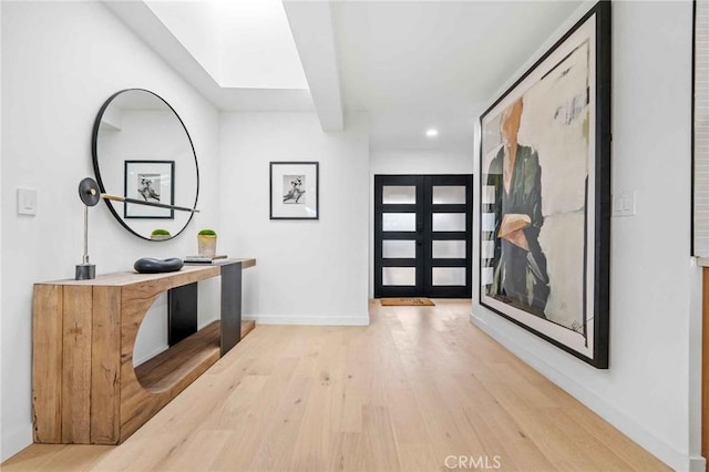 foyer entrance featuring a skylight, light hardwood / wood-style floors, and french doors