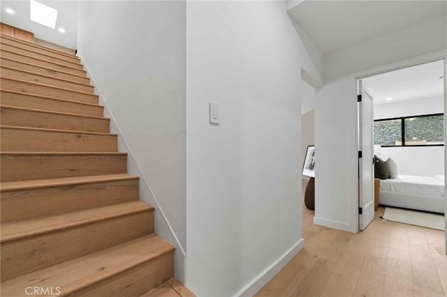 staircase featuring wood-type flooring and a skylight