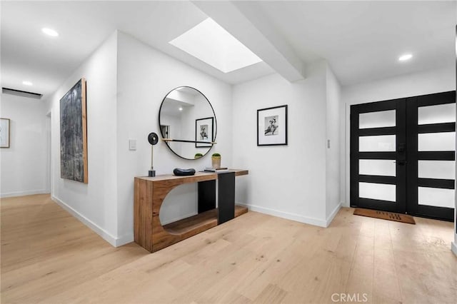 entrance foyer with french doors, a skylight, and light hardwood / wood-style flooring