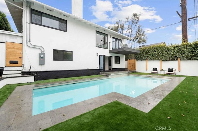 rear view of property with a lawn and a balcony