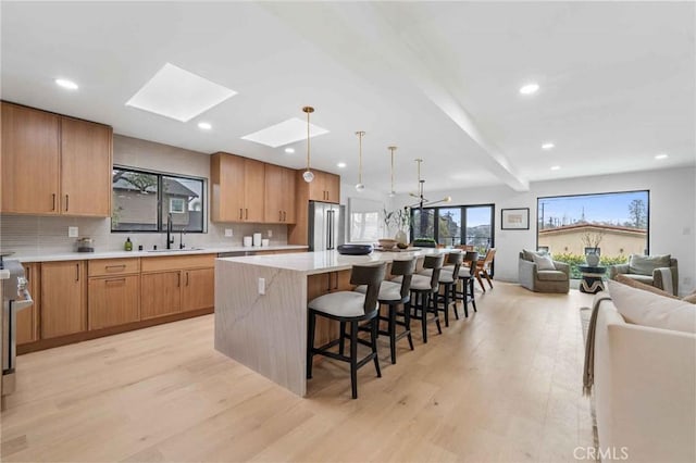 kitchen with a kitchen island, high quality fridge, a skylight, sink, and a kitchen breakfast bar