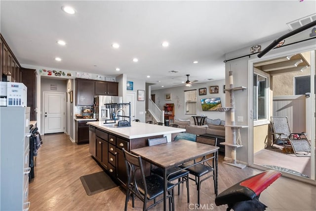 kitchen featuring dark brown cabinets, a center island with sink, stainless steel refrigerator, and light hardwood / wood-style flooring