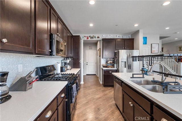 kitchen featuring dark brown cabinetry, sink, light wood-type flooring, appliances with stainless steel finishes, and decorative backsplash