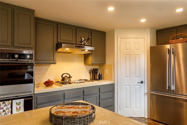 kitchen with tasteful backsplash, appliances with stainless steel finishes, and tile countertops