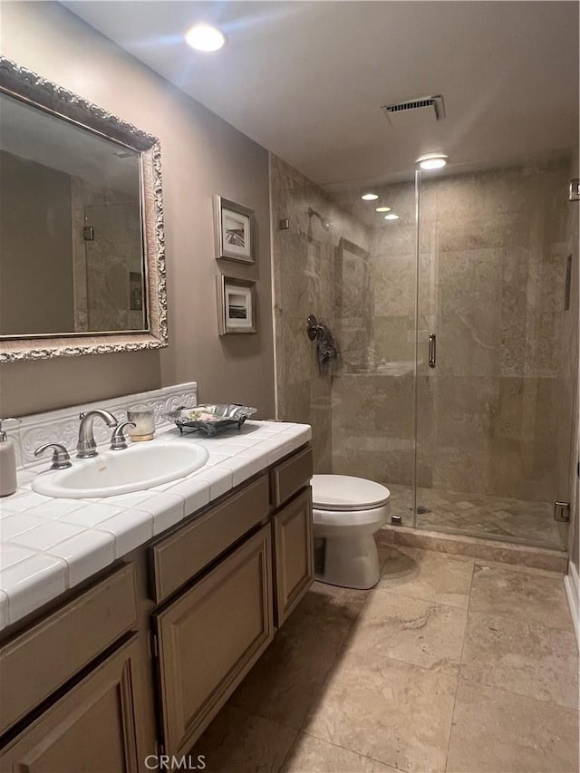 bathroom with vanity, a shower with shower door, and toilet