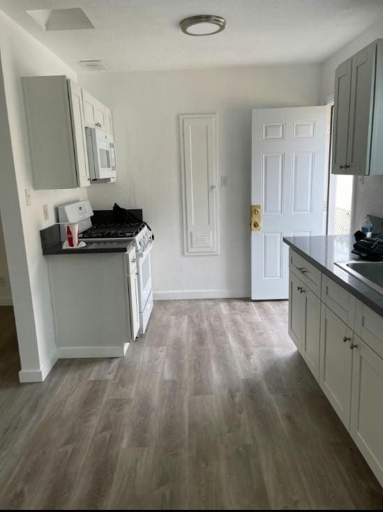 kitchen with gray cabinets, dark hardwood / wood-style flooring, sink, and white appliances