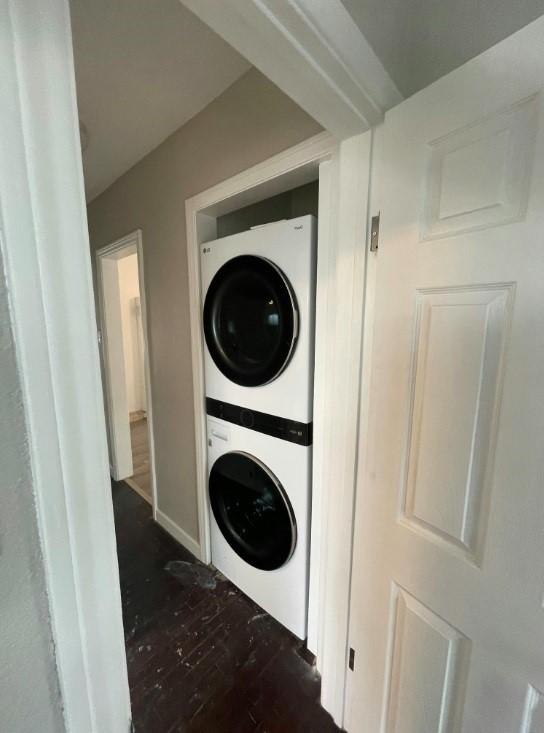 laundry area featuring stacked washer and dryer and dark hardwood / wood-style floors