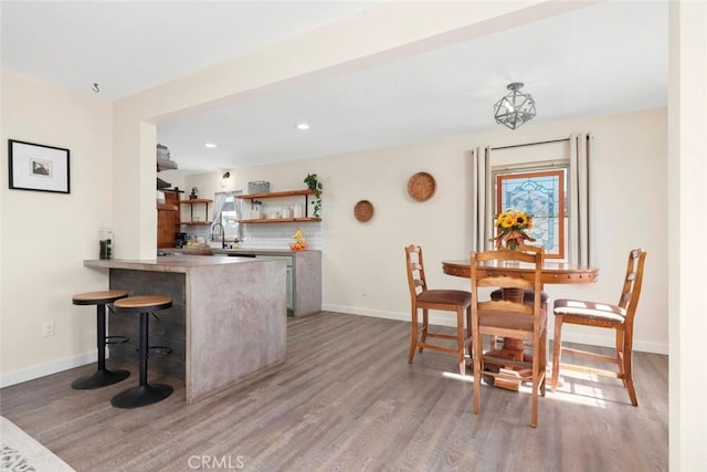 kitchen with light hardwood / wood-style flooring, backsplash, a kitchen breakfast bar, and kitchen peninsula