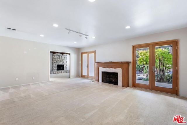 unfurnished living room with light carpet, a high end fireplace, and french doors