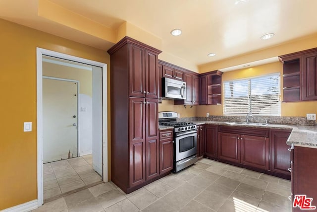 kitchen featuring light stone countertops, appliances with stainless steel finishes, sink, and light tile patterned floors