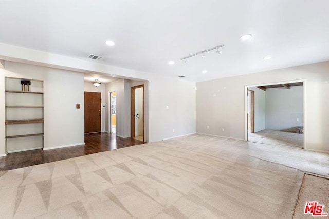 spare room featuring light colored carpet and rail lighting