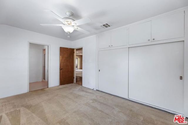 unfurnished bedroom featuring light carpet, ceiling fan, and a closet