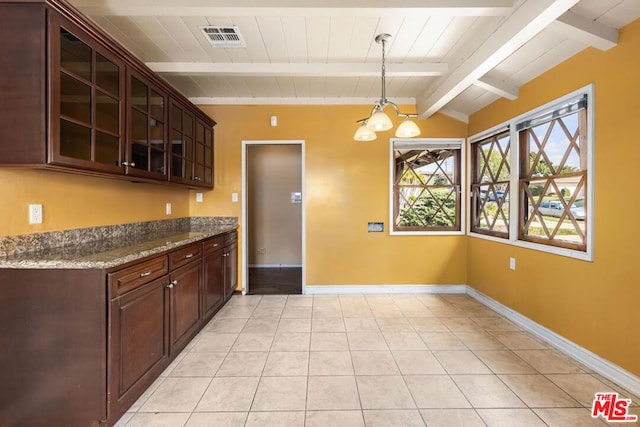 kitchen with pendant lighting, lofted ceiling with beams, light tile patterned floors, light stone countertops, and dark brown cabinets