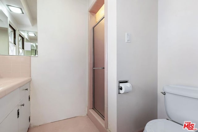 bathroom featuring a shower with door, vanity, backsplash, and toilet