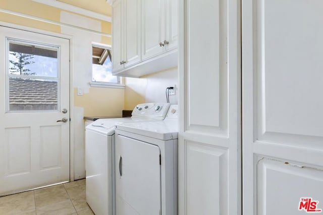 laundry area with washer and dryer, light tile patterned floors, and cabinets