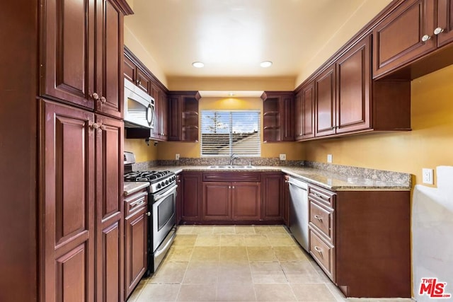 kitchen with appliances with stainless steel finishes, sink, light tile patterned floors, and light stone counters