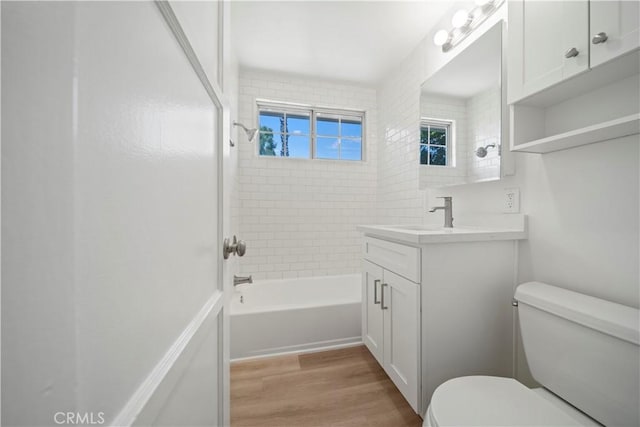 full bathroom featuring wood-type flooring, tiled shower / bath, vanity, and toilet