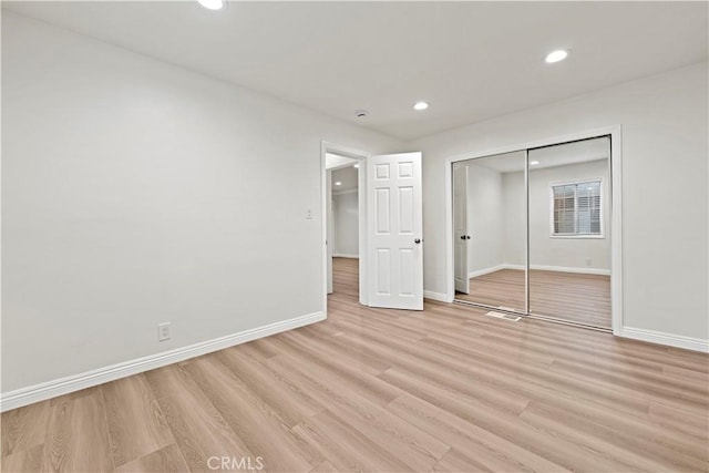 unfurnished bedroom featuring a closet and light wood-type flooring