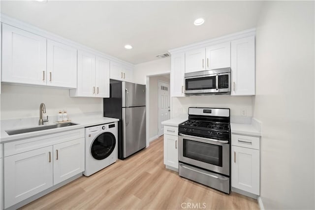 kitchen featuring stainless steel appliances, washer / clothes dryer, sink, and white cabinets