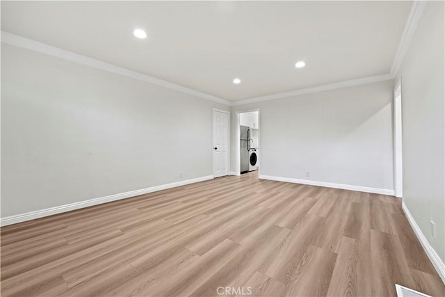 unfurnished living room featuring crown molding, stacked washing maching and dryer, and light hardwood / wood-style flooring