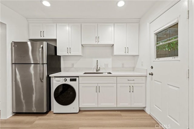 kitchen featuring white cabinetry, stainless steel fridge, washer / dryer, and sink